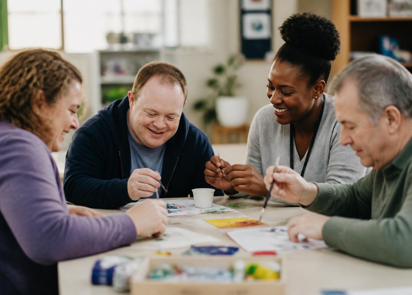 A small group taking part in an art activity around a table at a community centre with a support worker.